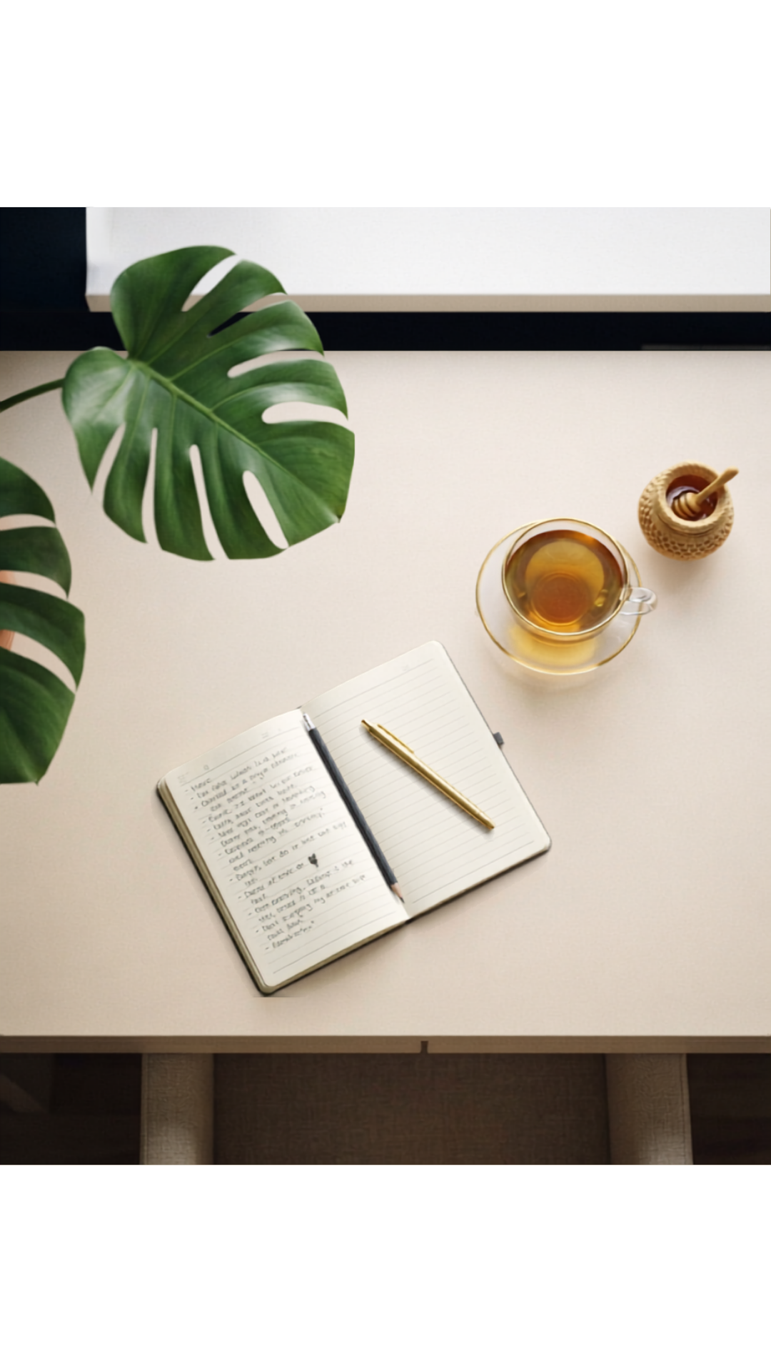 Vue du dessus : carnet ouvert, thé, miel et feuilles de monstera